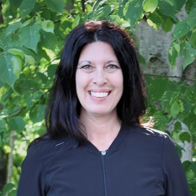 Amanda outside smiling in from of greenery.