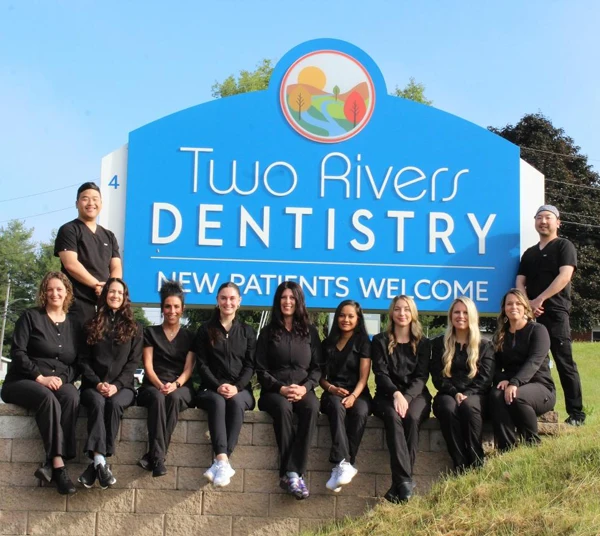 Dennis Shim outside in front of the clinic sign, with his team.