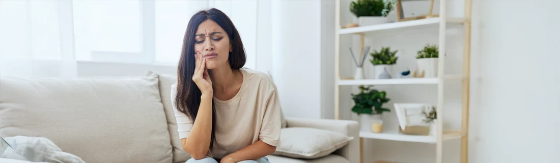 A woman holding her mouth in pain.