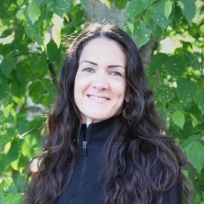 Kara outside smiling in from of greenery.