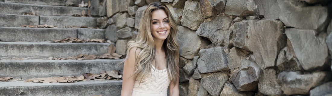 A woman smiling while sitting on stone stairs.