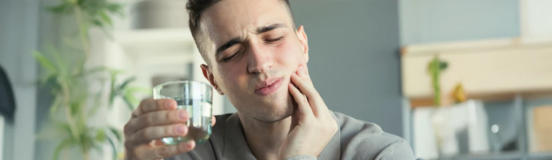 A man holding his mouth in pain.
